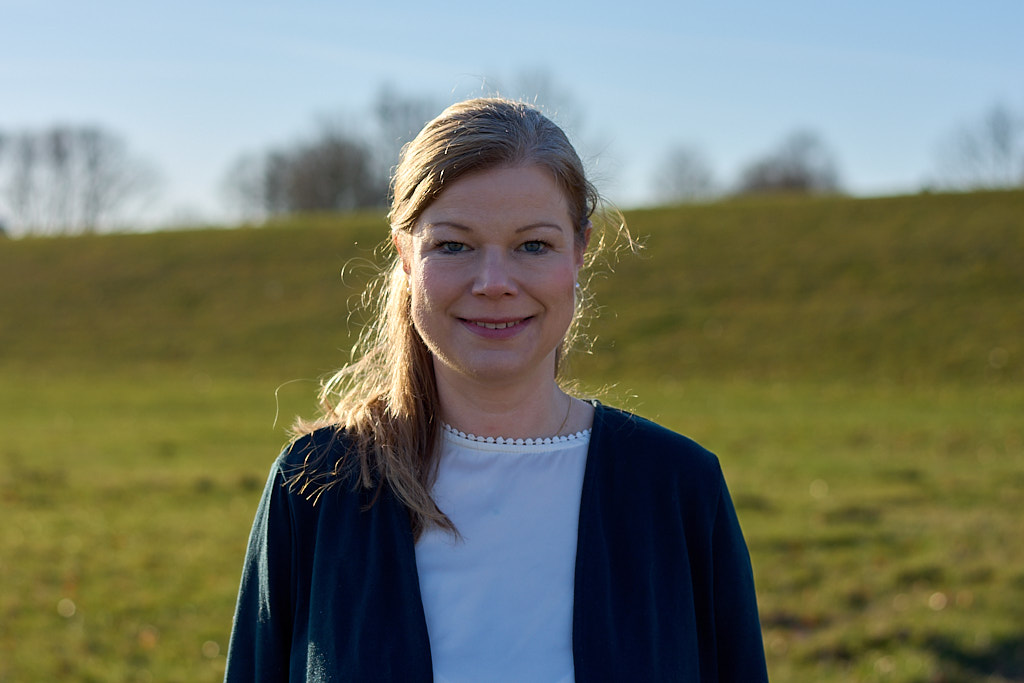 Portrait von Dr. med. Annegret Chao. Sie lächelt in die Kamera und steht vor einem verschwommenen Deich-Hintergrund.